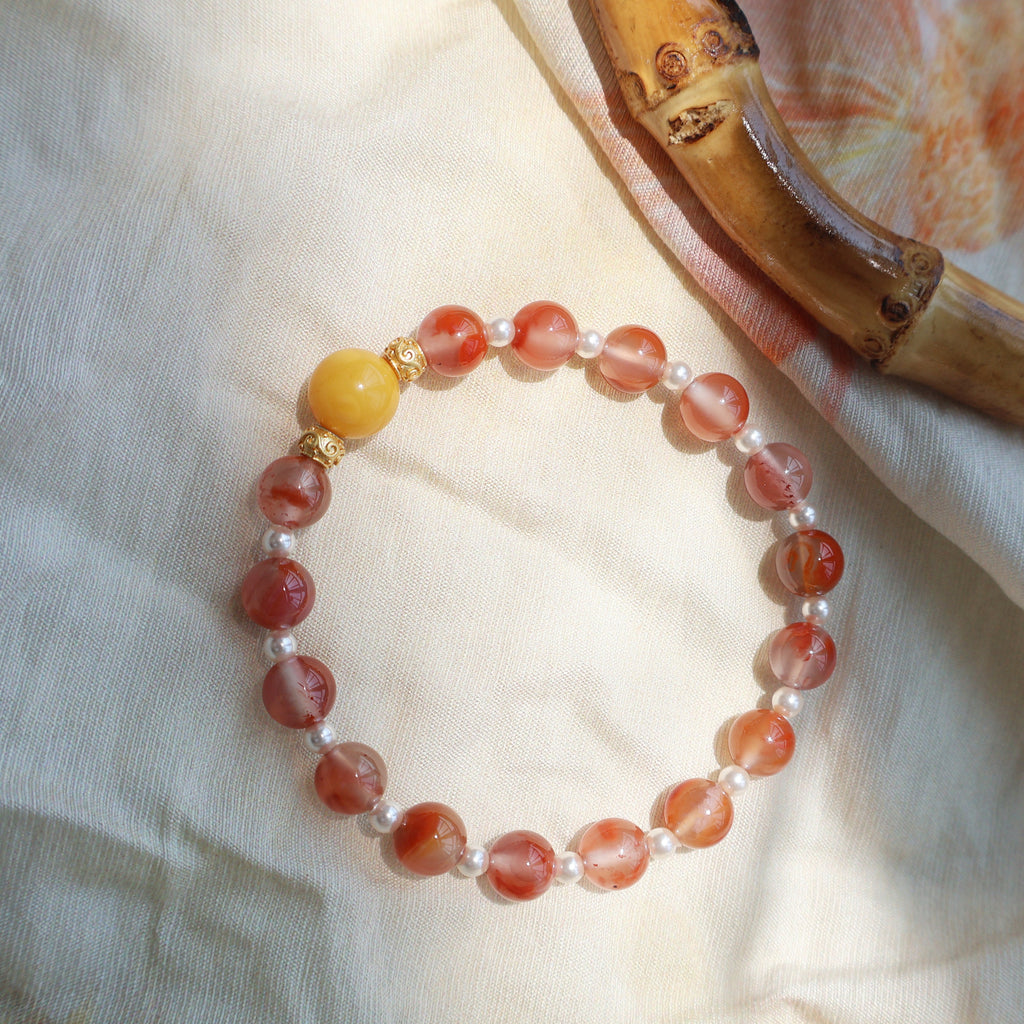 Beaded bracelet with red, yellow, and white beads on a light fabric background
