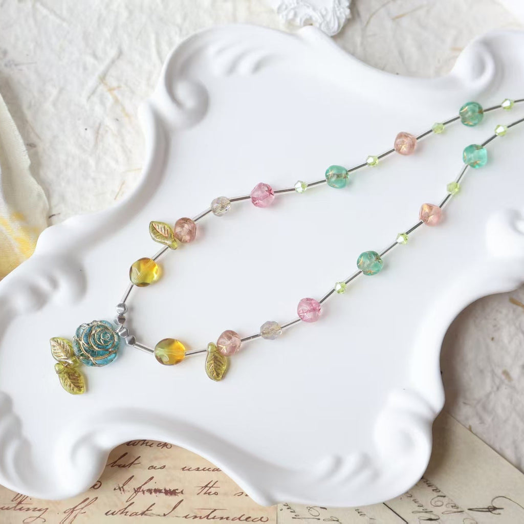 Colorful beaded necklace on a white decorative plate with a textured surface