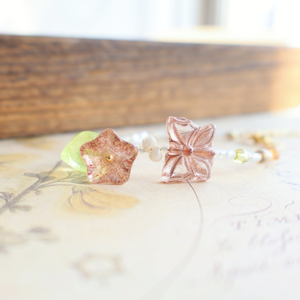 Rose gold flower-shaped glass bead on a white surface with a blurred background