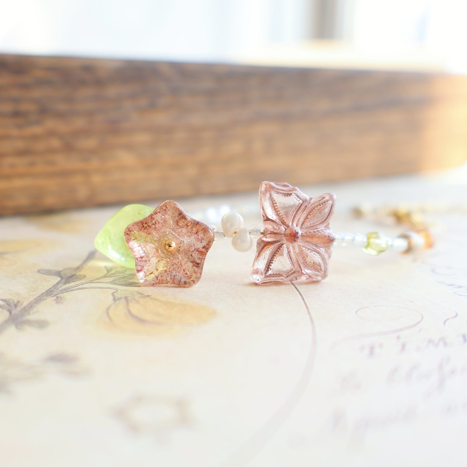 Rose gold flower-shaped glass bead on a white surface with a blurred background