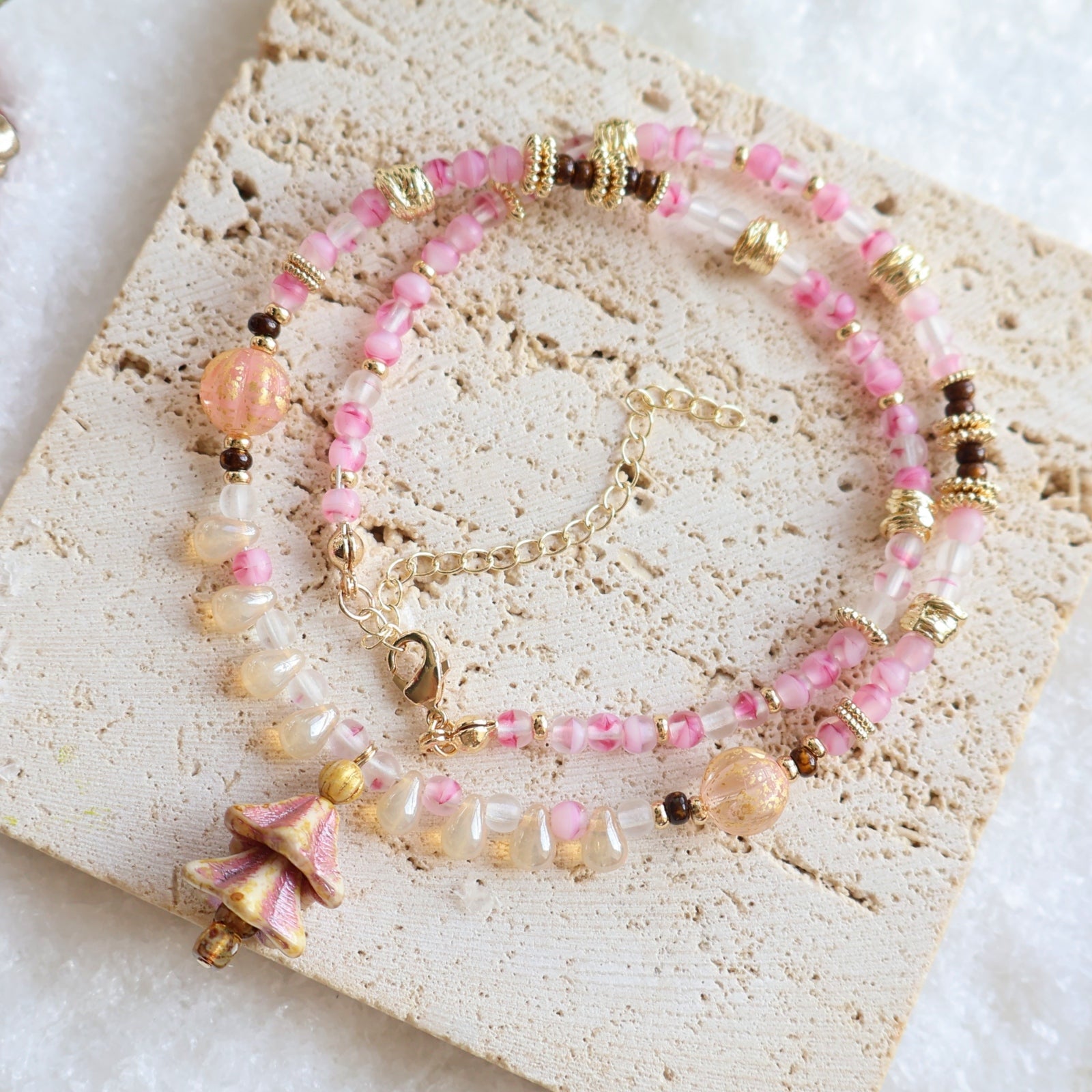 Pink and gold beaded bracelet on a textured stone surface