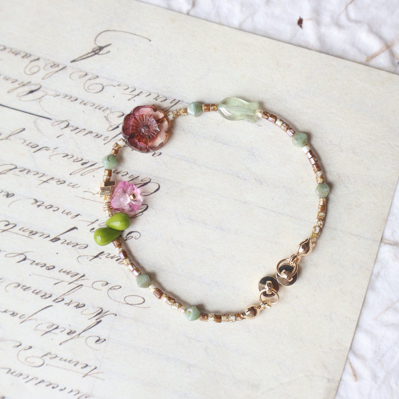 Bracelet with floral and green beads on a textured paper background