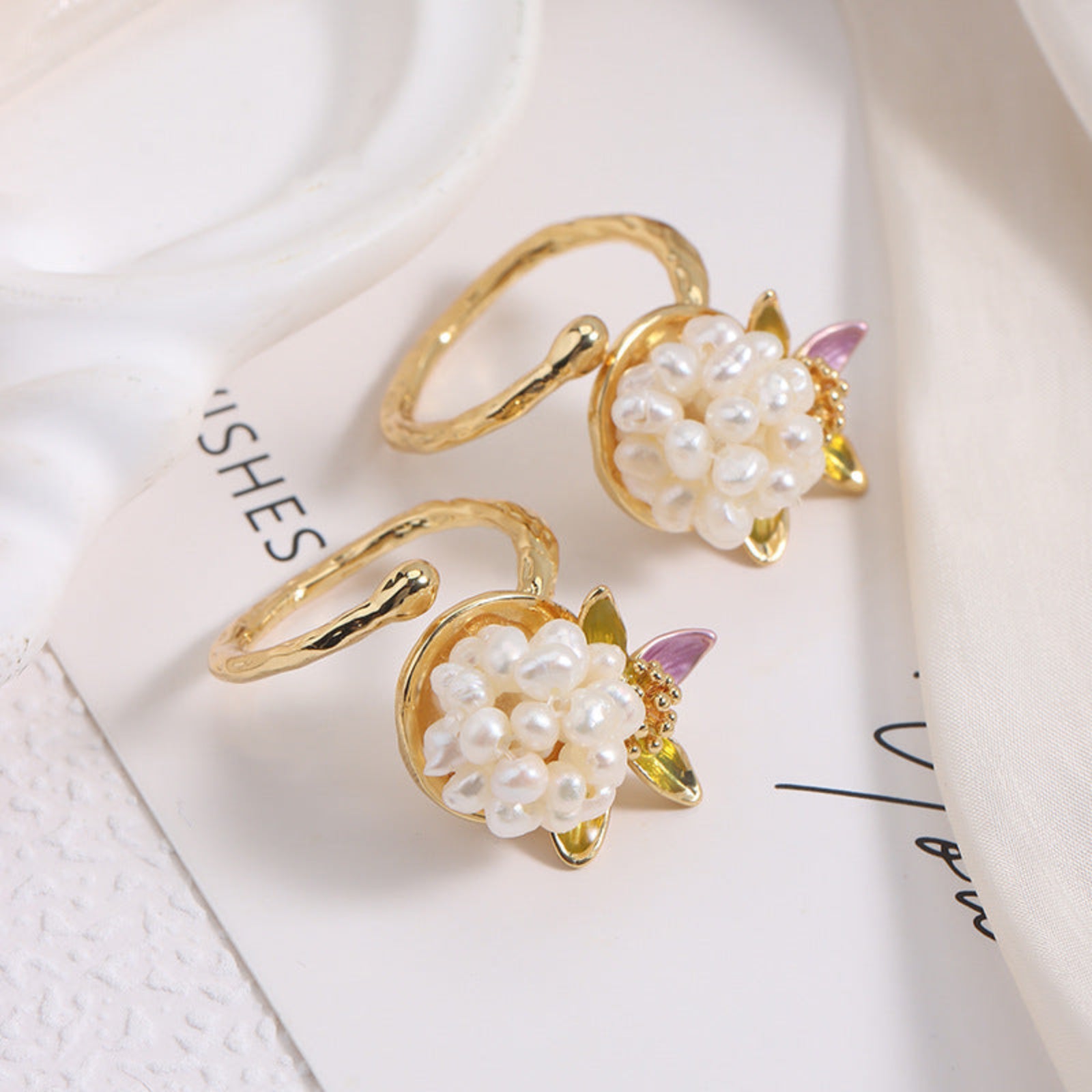 Gold hoop earrings with pearl-like bead embellishments on a light background