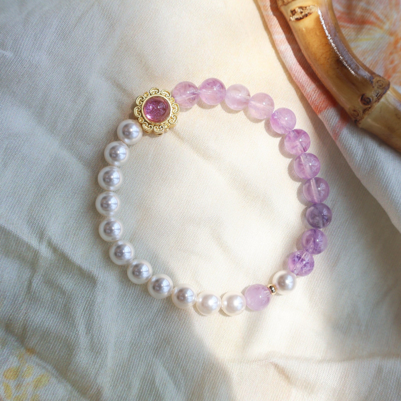 Beaded bracelet with pink and white pearls on a light fabric background