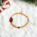 Colorful beaded bracelet on a snowy surface with Christmas decorations.