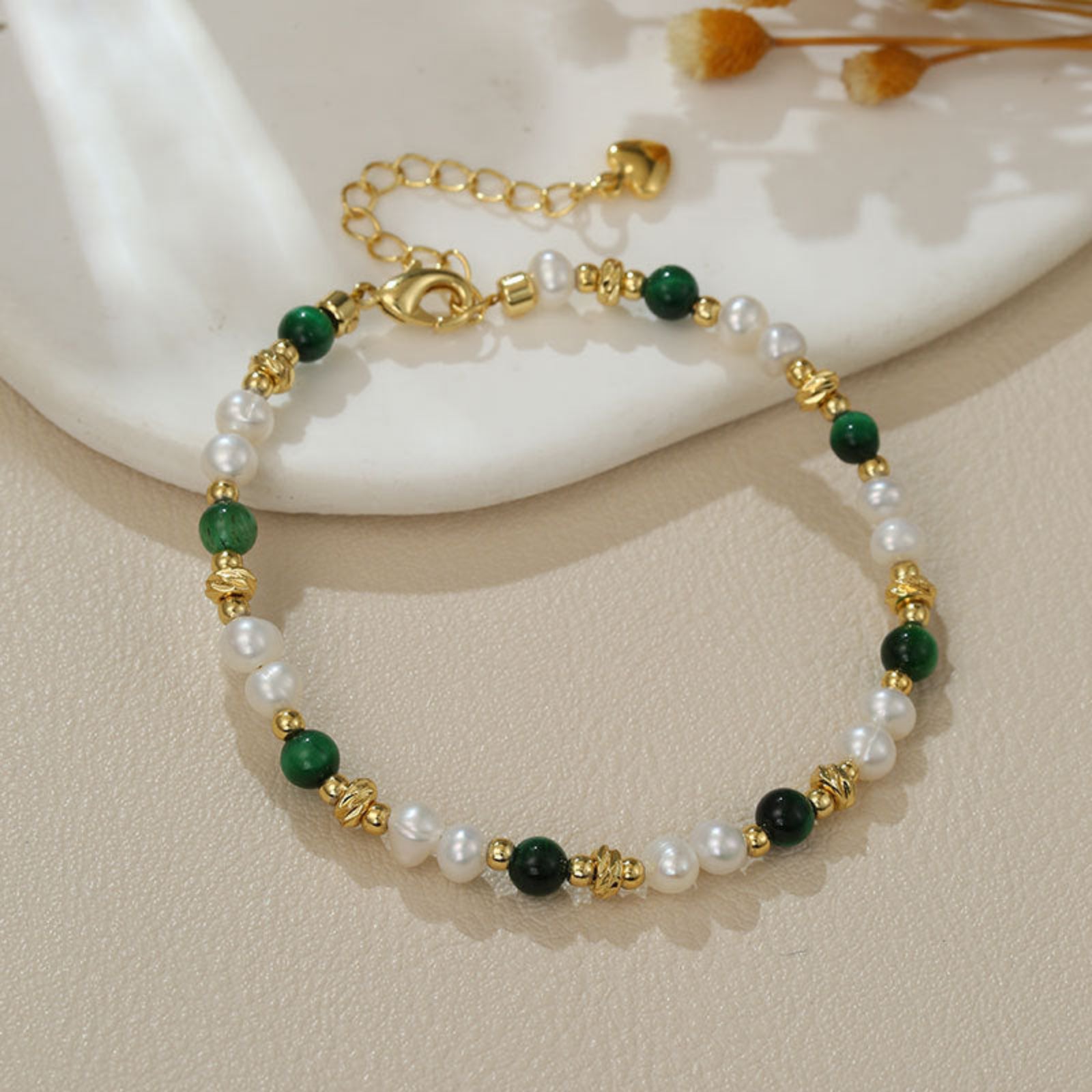 Bracelet with green, white, and gold beads on a neutral background