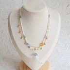 Necklace with beads and tassel on a mannequin bust against a textured white background