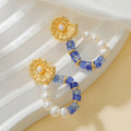 Pair of earrings with gold, blue, and pearl design on a white background