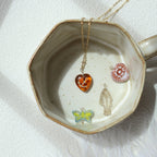 Jewelry dish with various necklaces featuring heart, butterfly, and floral pendants on a white background.