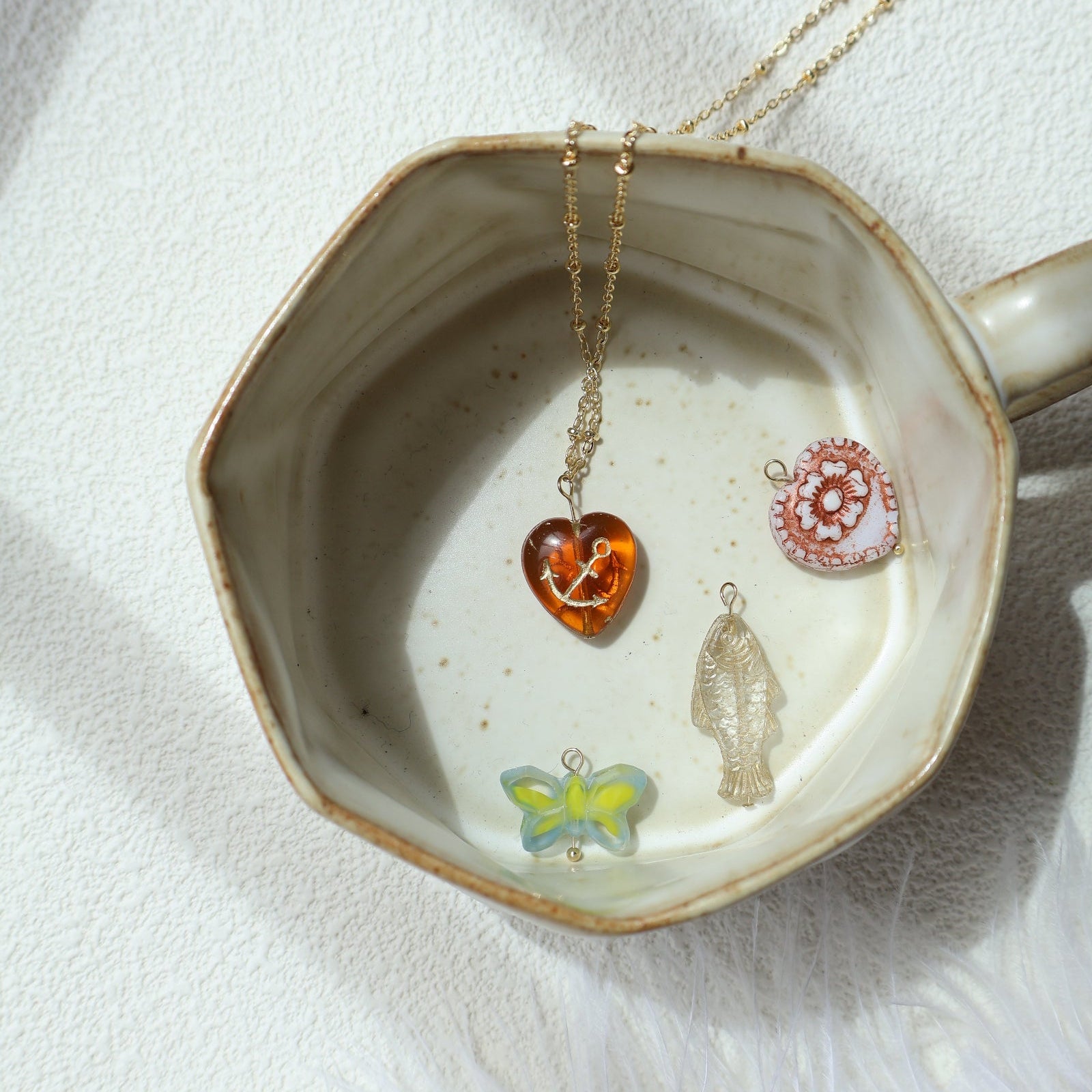 Jewelry dish with various necklaces featuring heart, butterfly, and floral pendants on a white background.