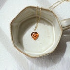 Necklace with a heart-shaped amber pendant on a ceramic dish