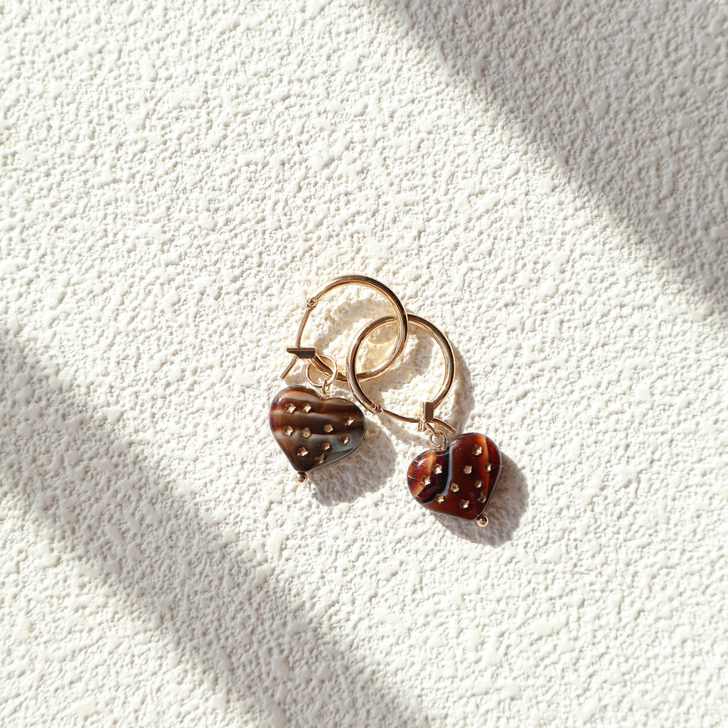 Pair of earrings with ladybug design on a textured white surface