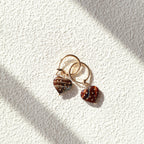 Pair of earrings with ladybug design on a textured white surface