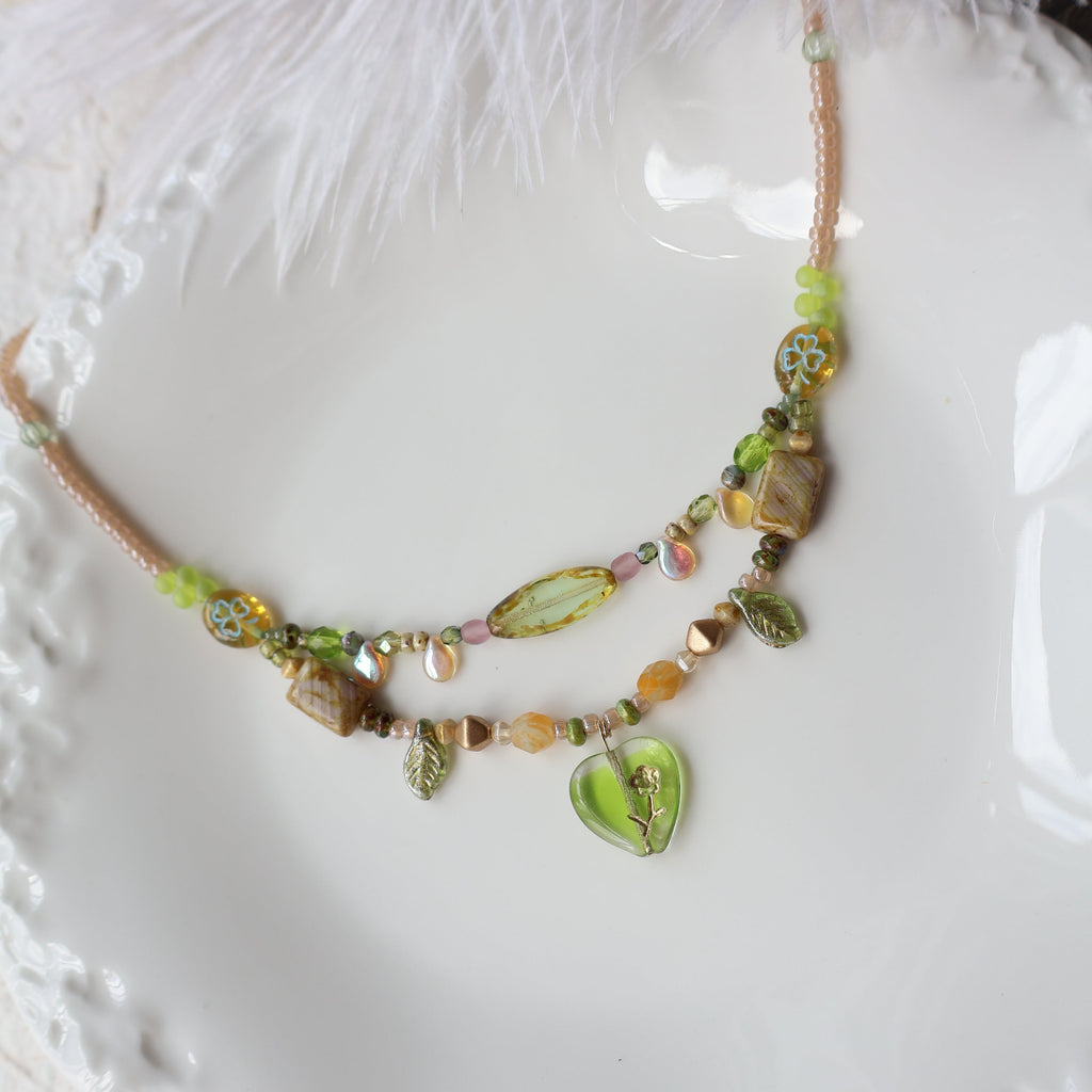 Necklace with green and brown beads on a white textured surface
