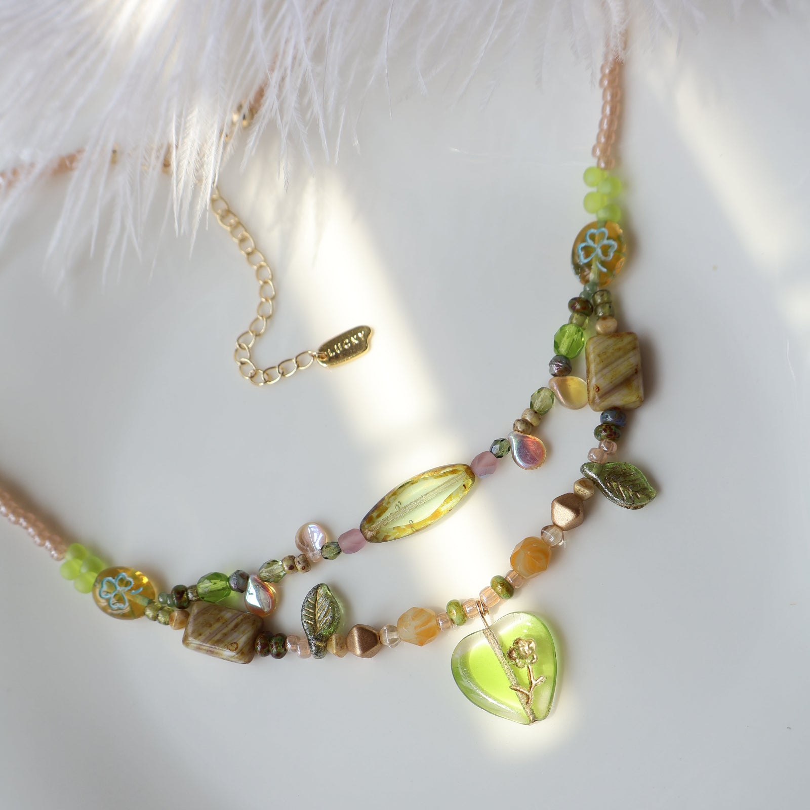 Necklace with green and gold beads on a white surface