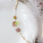 Necklace with colorful beads on a white shell and feather background