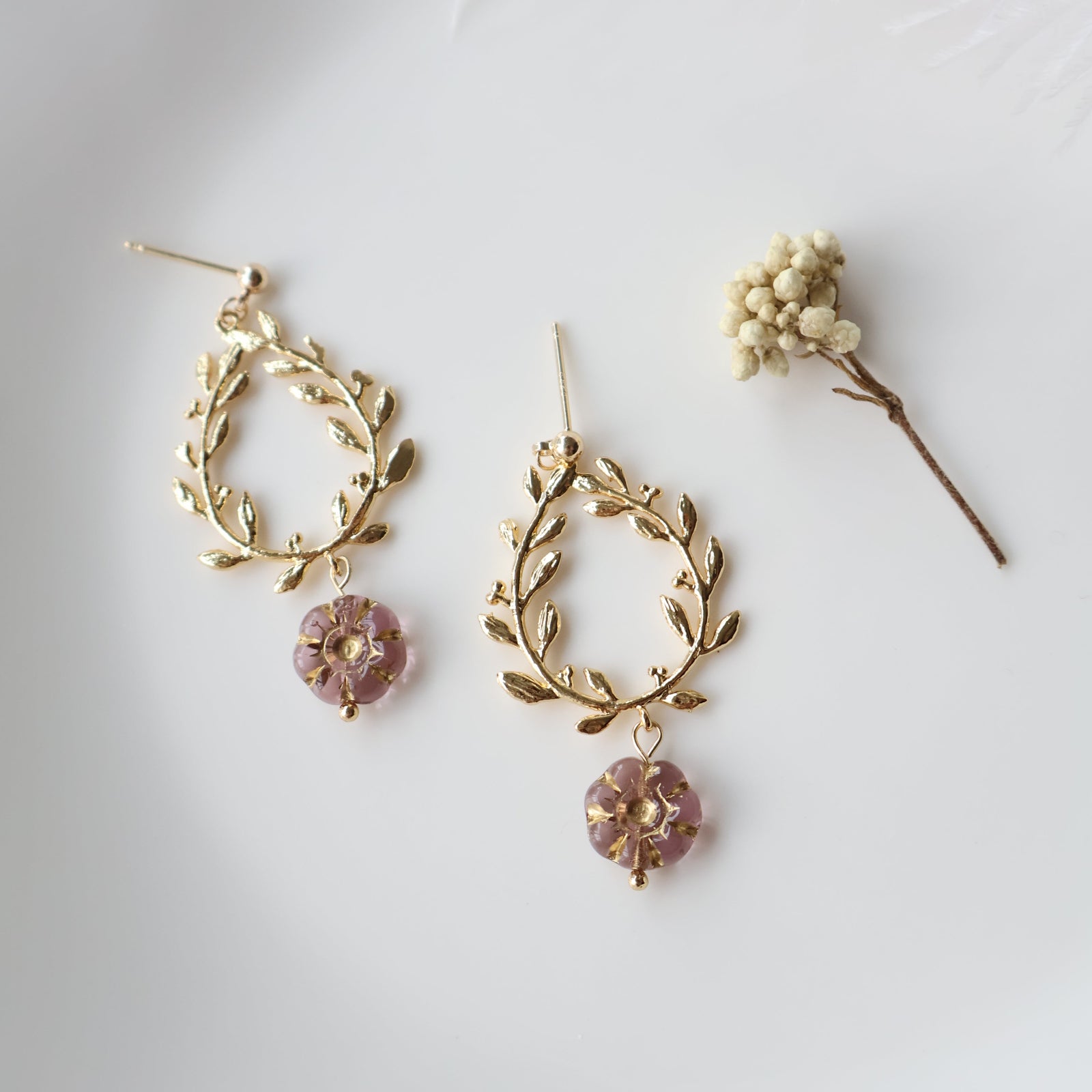 Pair of gold earrings with floral designs on a white background