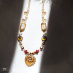 Decorative necklace with beads and gold elements on a reflective surface
