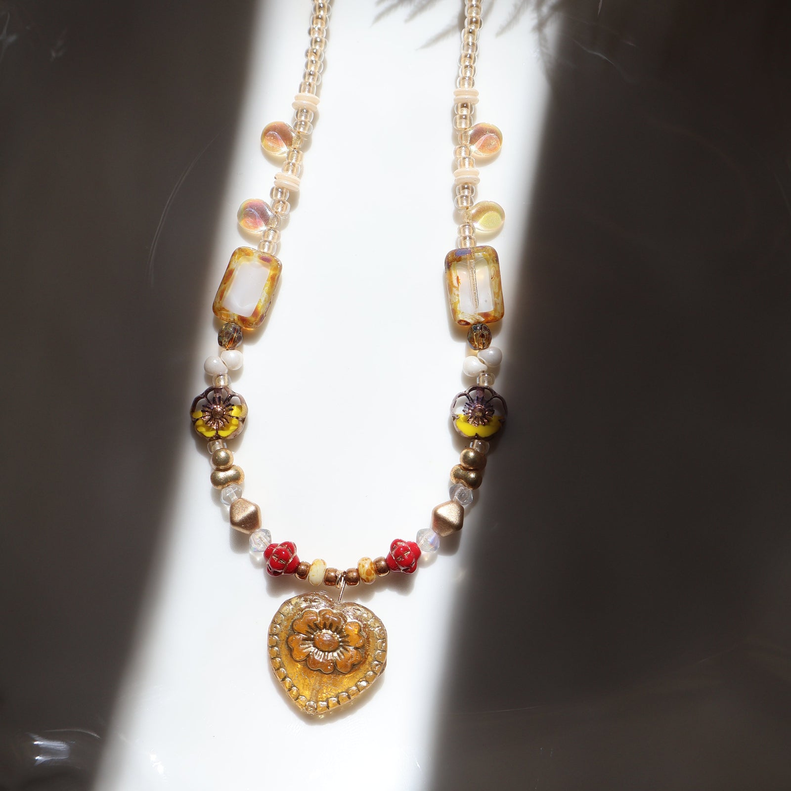 Decorative necklace with beads and gold elements on a reflective surface
