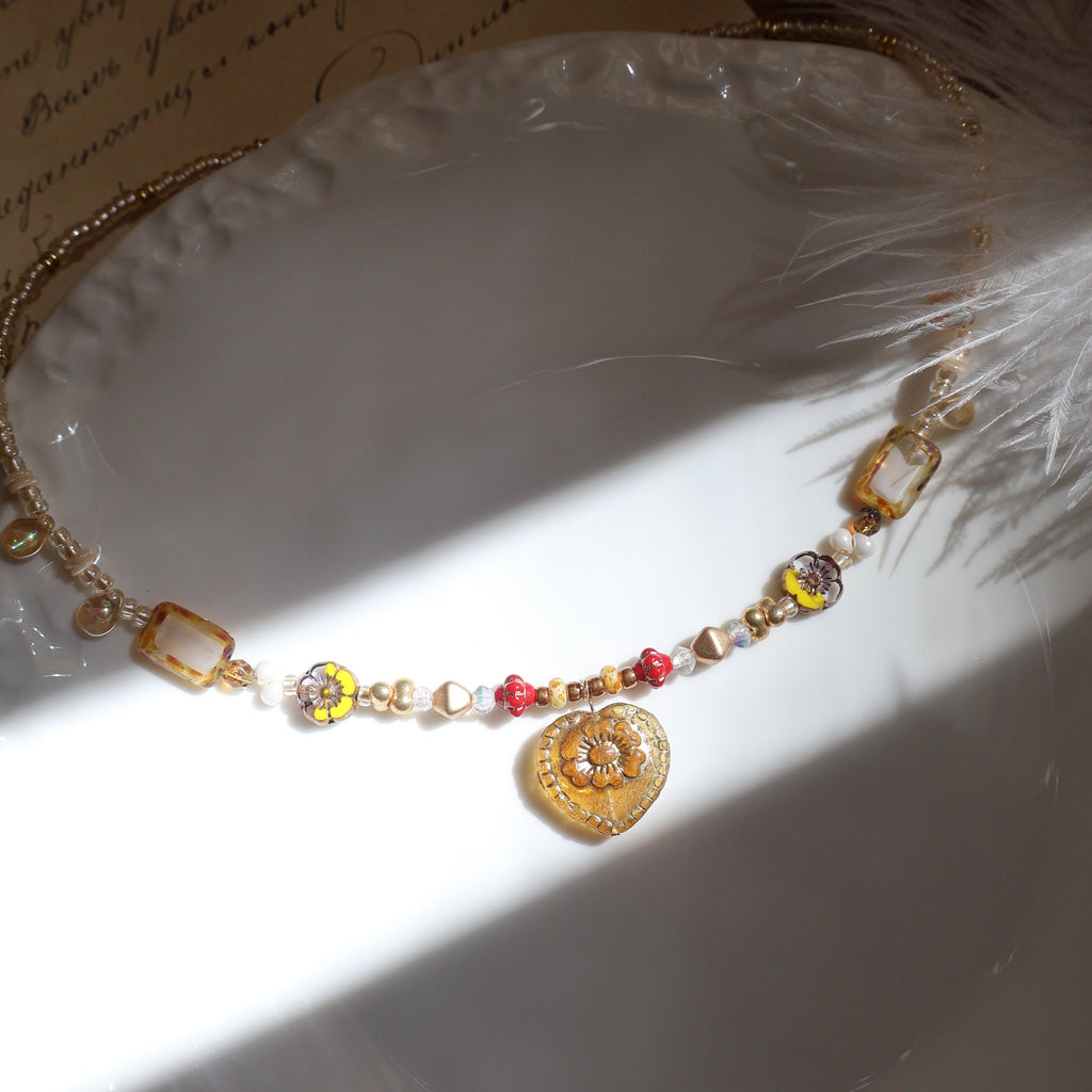 Necklace with colorful beads on a white shell and feather