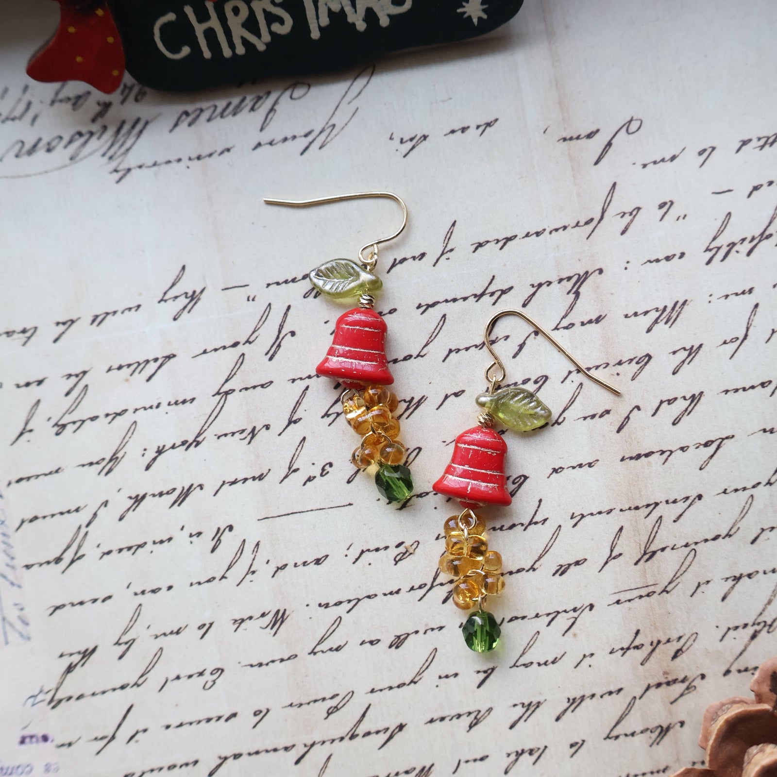 Christmas-themed earrings on a piece of paper with cursive writing