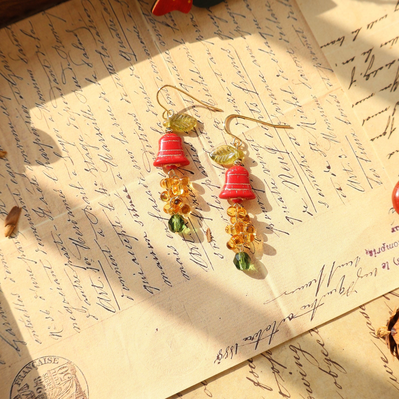Colorful earrings on an old letter with a pen and decorative item.