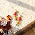Pair of earrings with red and green elements on a textured surface