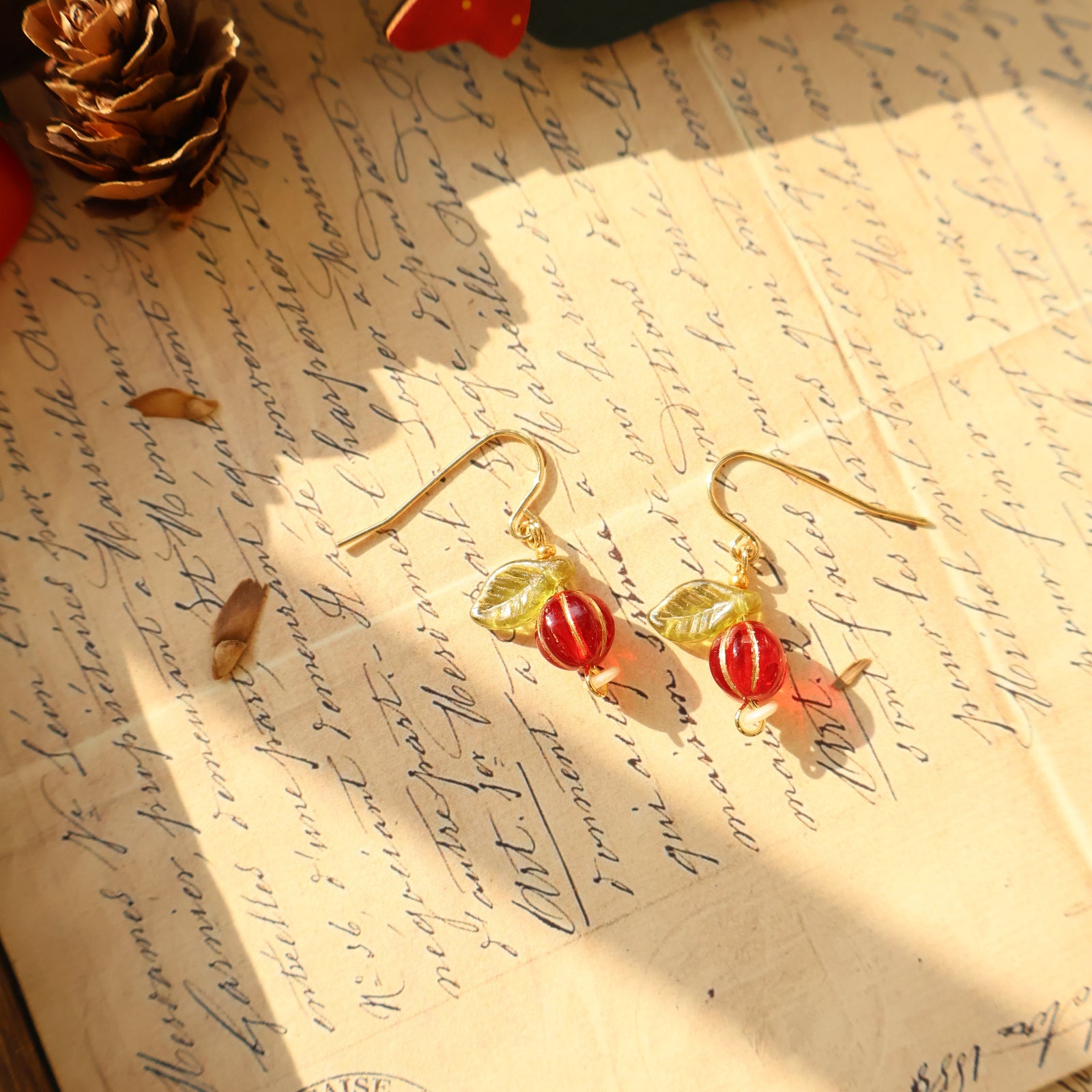 Gold earrings with red and green accents on a vintage letter