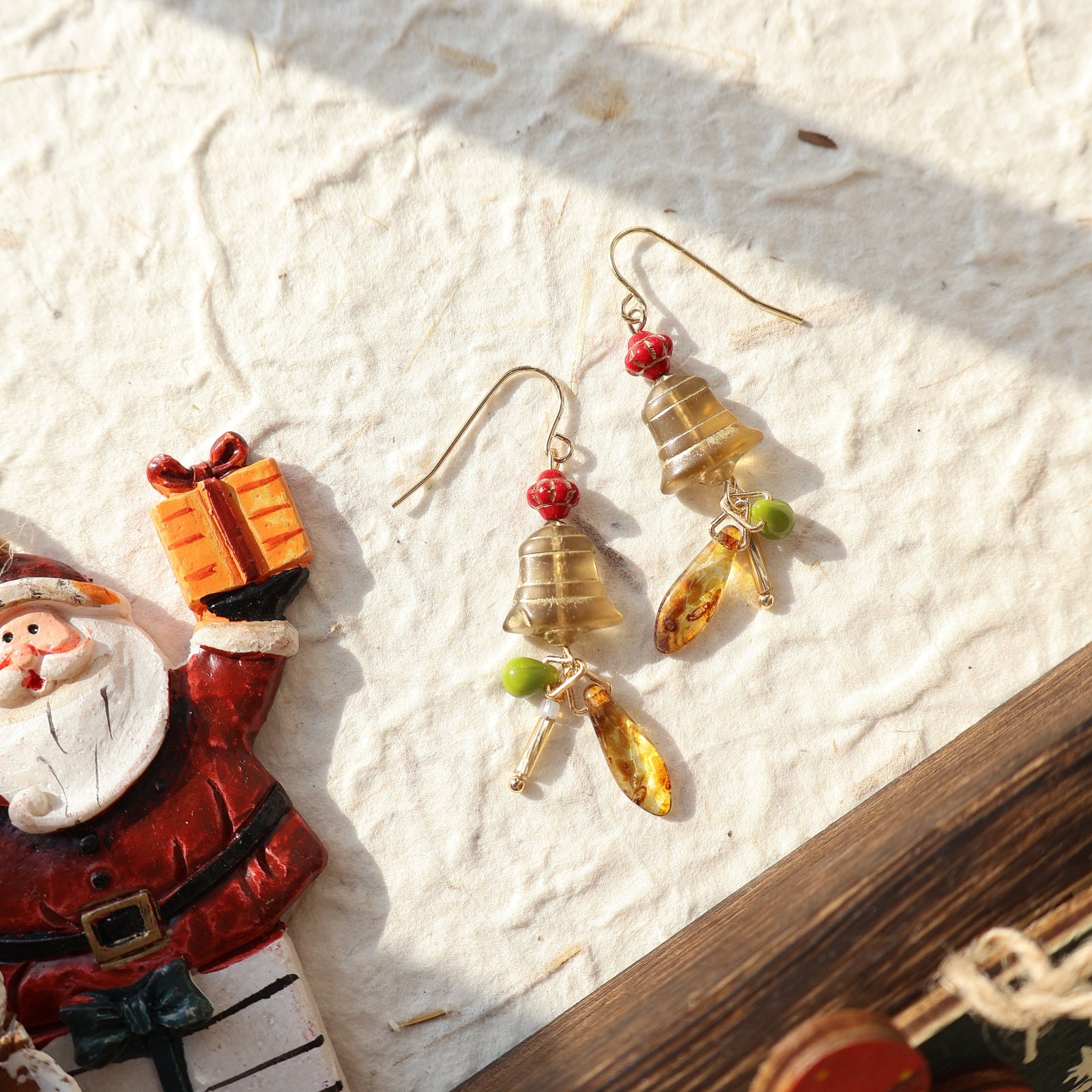 Pair of earrings with gemstones on a textured surface with Christmas decorations.