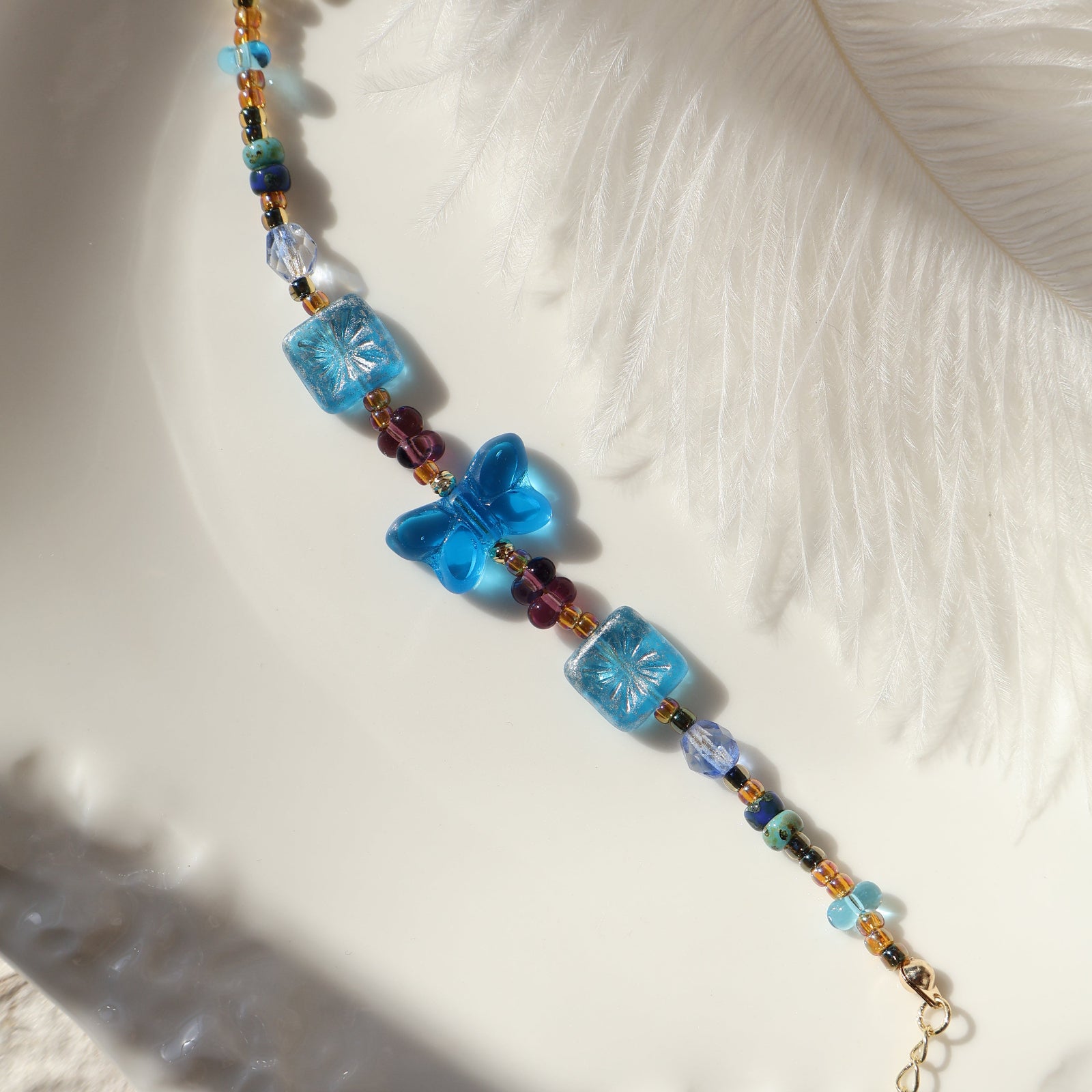 Beaded bracelet with blue butterfly beads on a textured white surface
