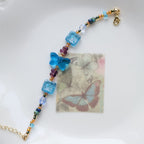 Necklace with colorful beads on a white dish with butterfly-themed paper