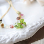 Close-up of a decorative brooch with green gemstones on a blurred background