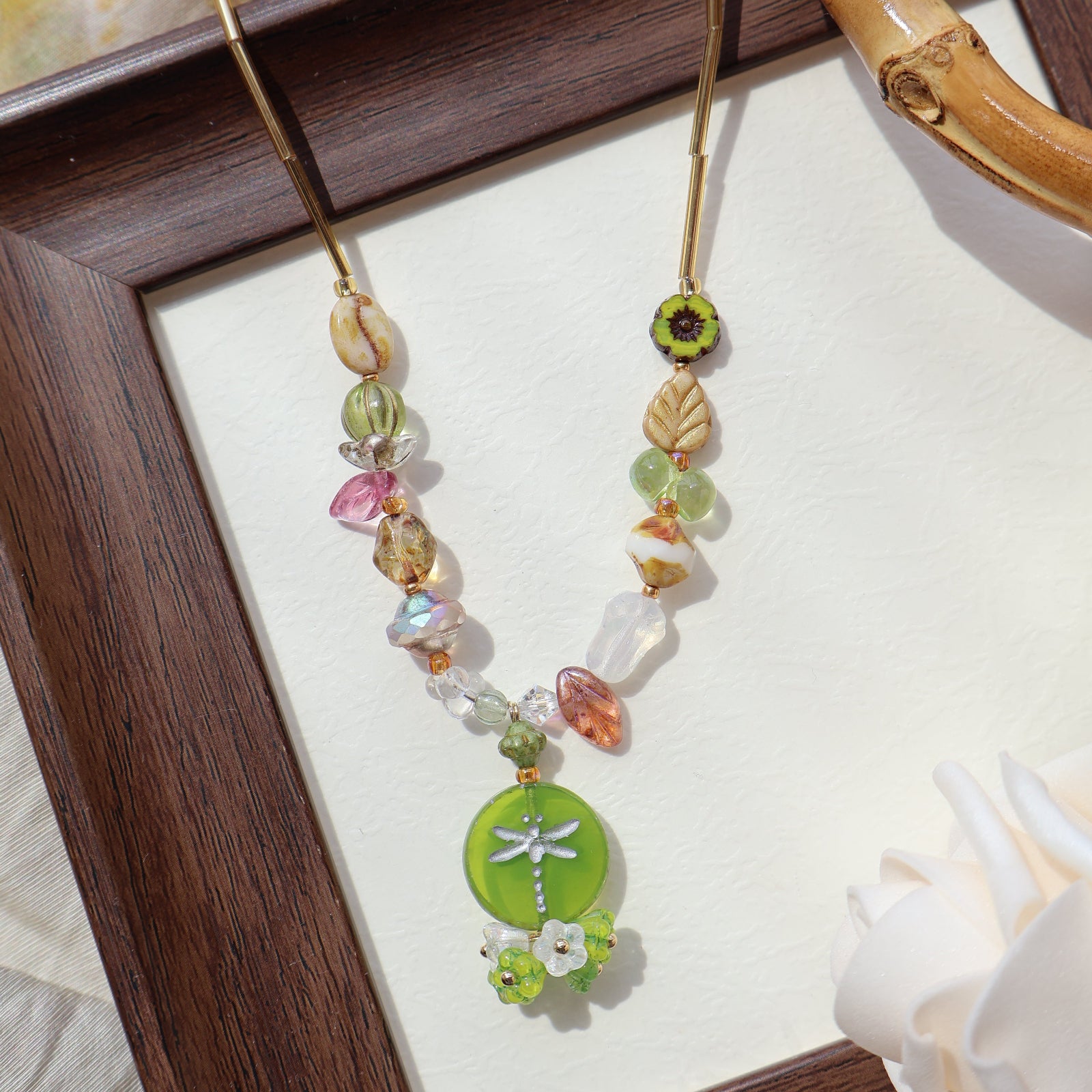Decorative hairpin with colorful beads and a green dragonfly design in a wooden frame.