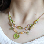 Close-up of a person wearing a colorful beaded necklace with leaf-shaped beads.
