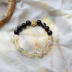 Bracelet with black beads and a gold clasp on a light fabric background