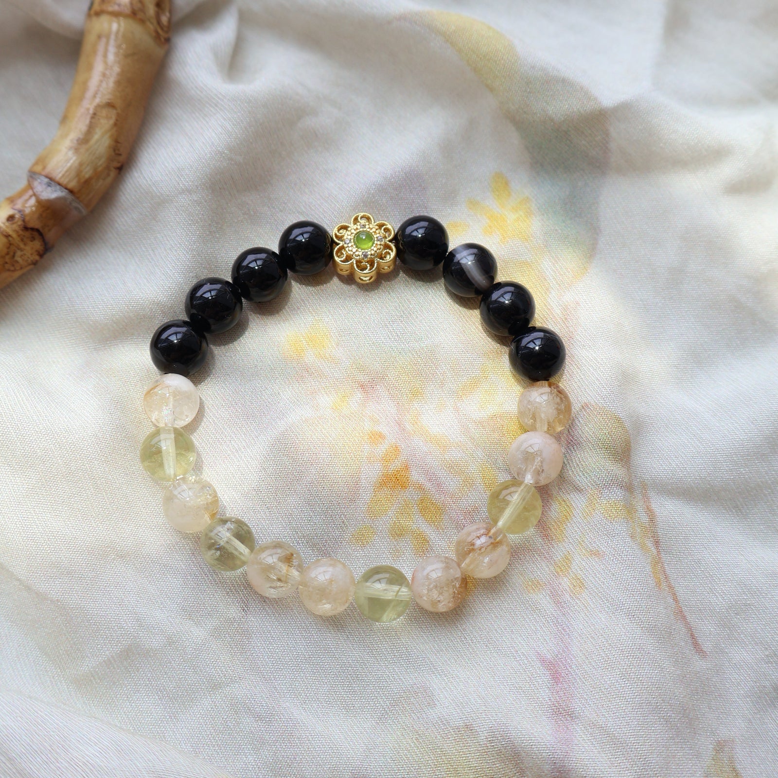 Bracelet with black beads and a gold clasp on a light fabric background
