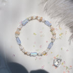 Beaded bracelet with a heart-shaped crystal on a white surface with feathers