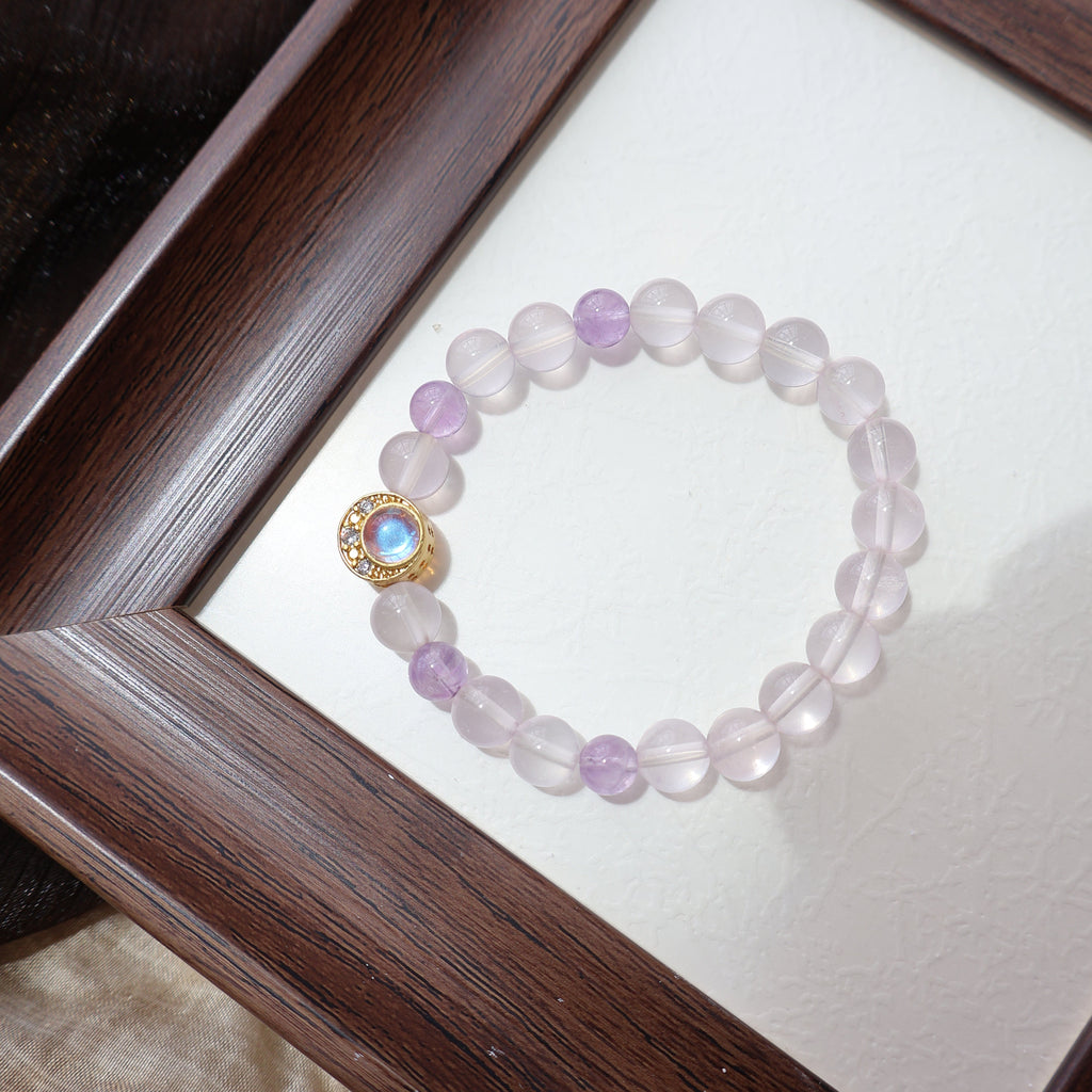 Bracelet with pink beads and gold clasp on a white card inside a wooden frame