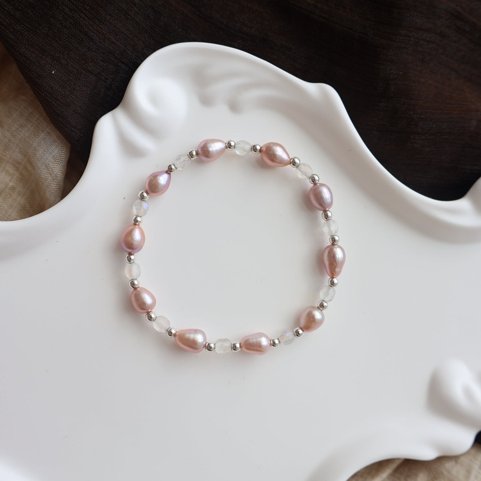 Pearl bracelet on a decorative white dish with a dark background
