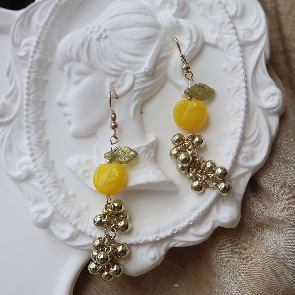 Yellow and gold earrings on a decorative white surface