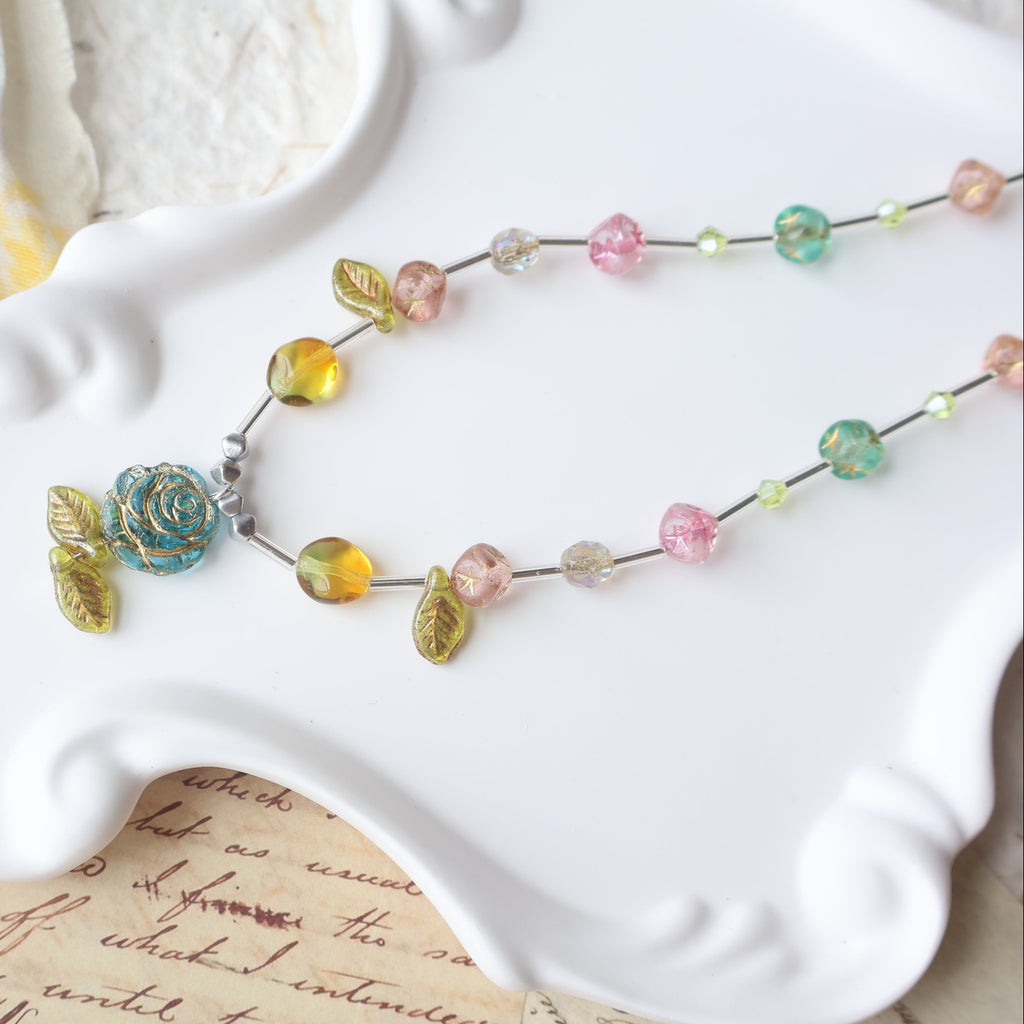 Colorful beaded necklace on a white dish with a textured fabric background