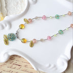 Colorful beaded necklace on a white dish with a textured fabric background