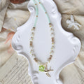 Necklace with green gemstone on a white decorative plate with a textured fabric background