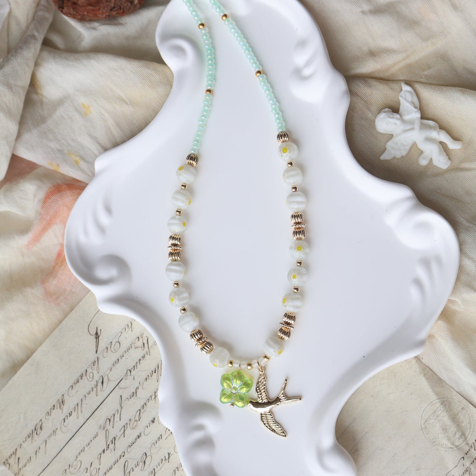 Necklace with green gemstone on a white decorative plate with a textured fabric background