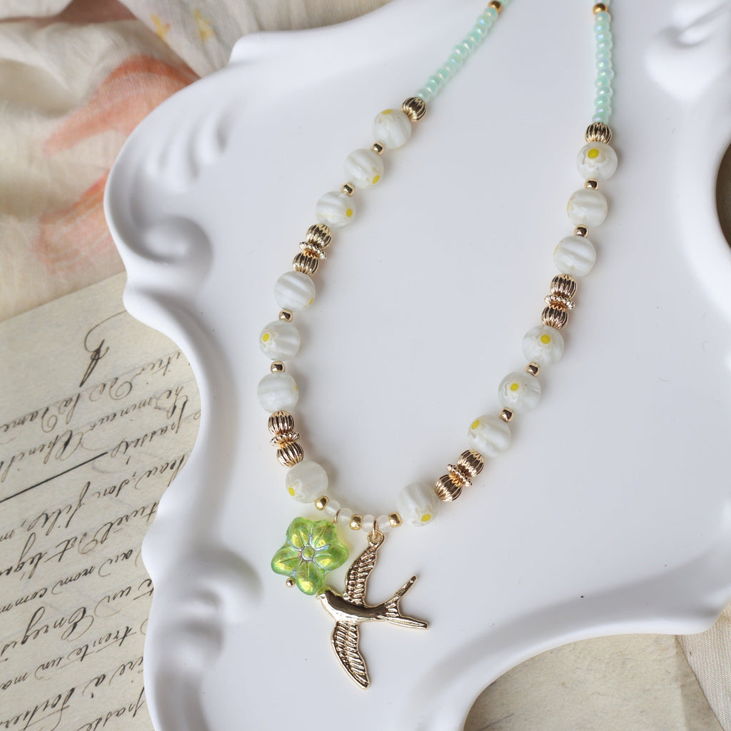 Decorative necklace with green leaf charm on a white dish