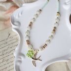 Decorative necklace with green leaf charm on a white dish
