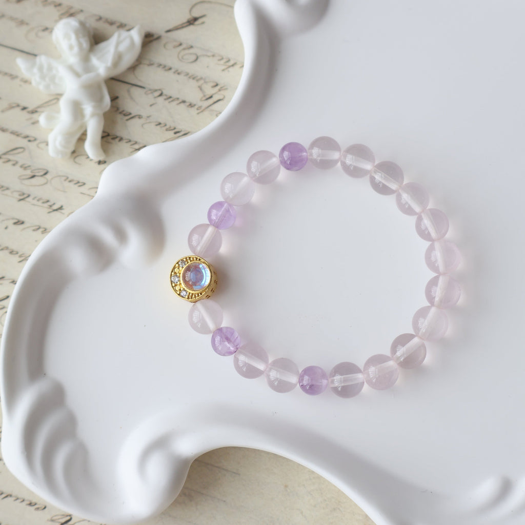 Pink beaded bracelet with a gold clasp on a white dish with a butterfly and text in the background