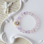 Pink beaded bracelet with a gold clasp on a white dish with a butterfly and text in the background