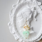 Decorative hairpin with green and gold elements on a white ornate plaque.