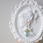 Decorative earring on a white ornate dish with a gray background